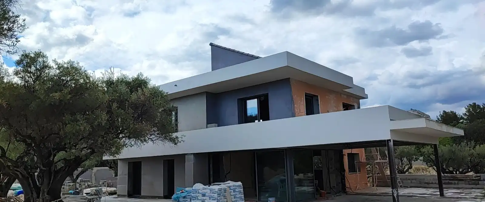 Villa en fin de chantier : façade enduite, échafaudage et matériaux au pied du mur