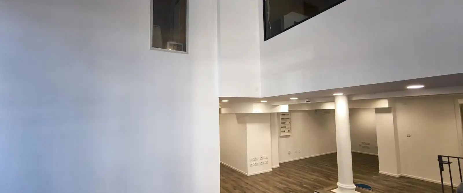 Plateau de bureaux après travaux : murs et plafonds peints, poteau habillé, mezzanine