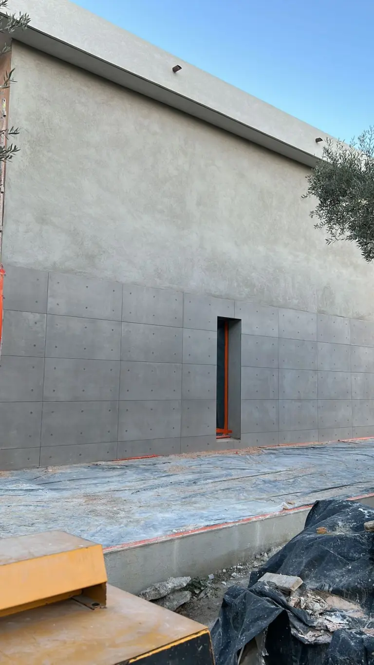 Mur de façade enduit en gris, panneaux marqués dans la partie basse