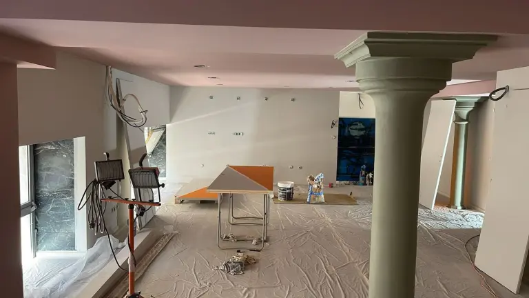 Locaux professionnels en cours de rénovation : sol protégé par une bâche, plaques de plâtre, projecteurs de chantier